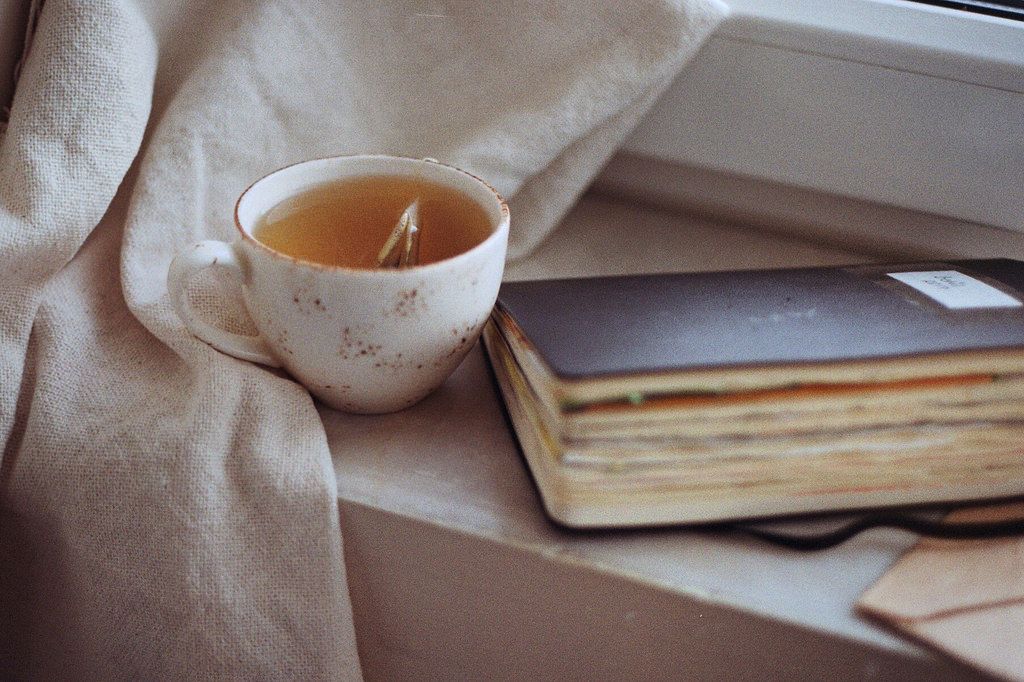 Muted morning tabletop with herbal tea beside a folded notebook representing calm rituals
